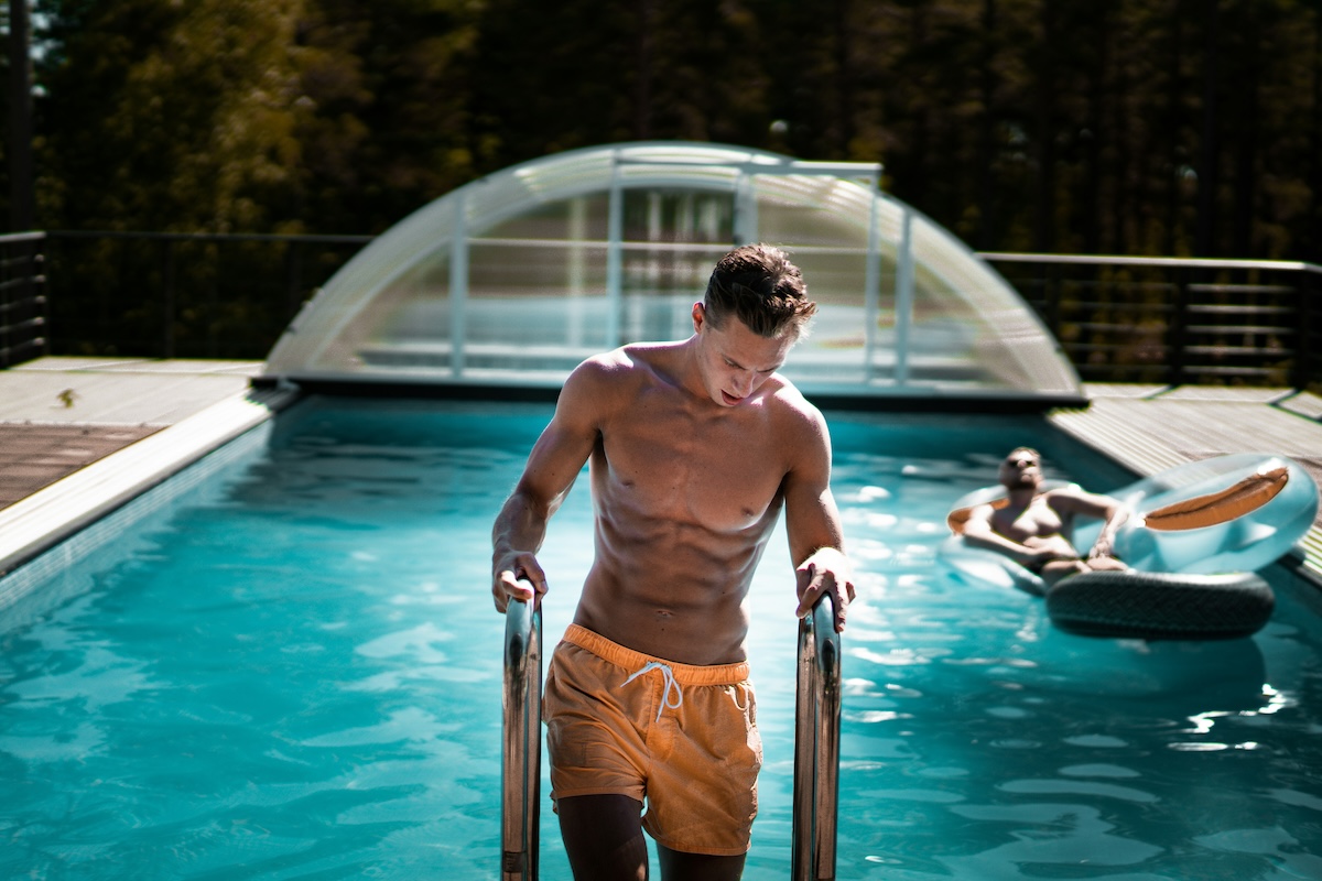 man getting out of pool with orange swim bottoms on