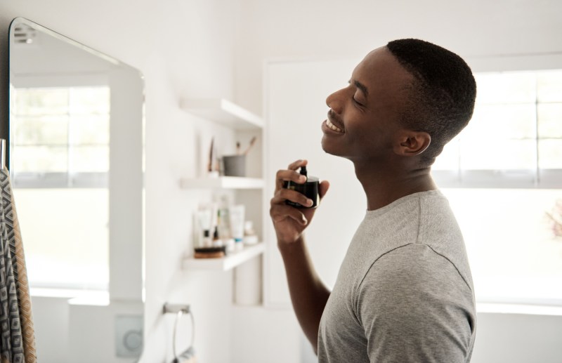 Person spraying cologne on their neck